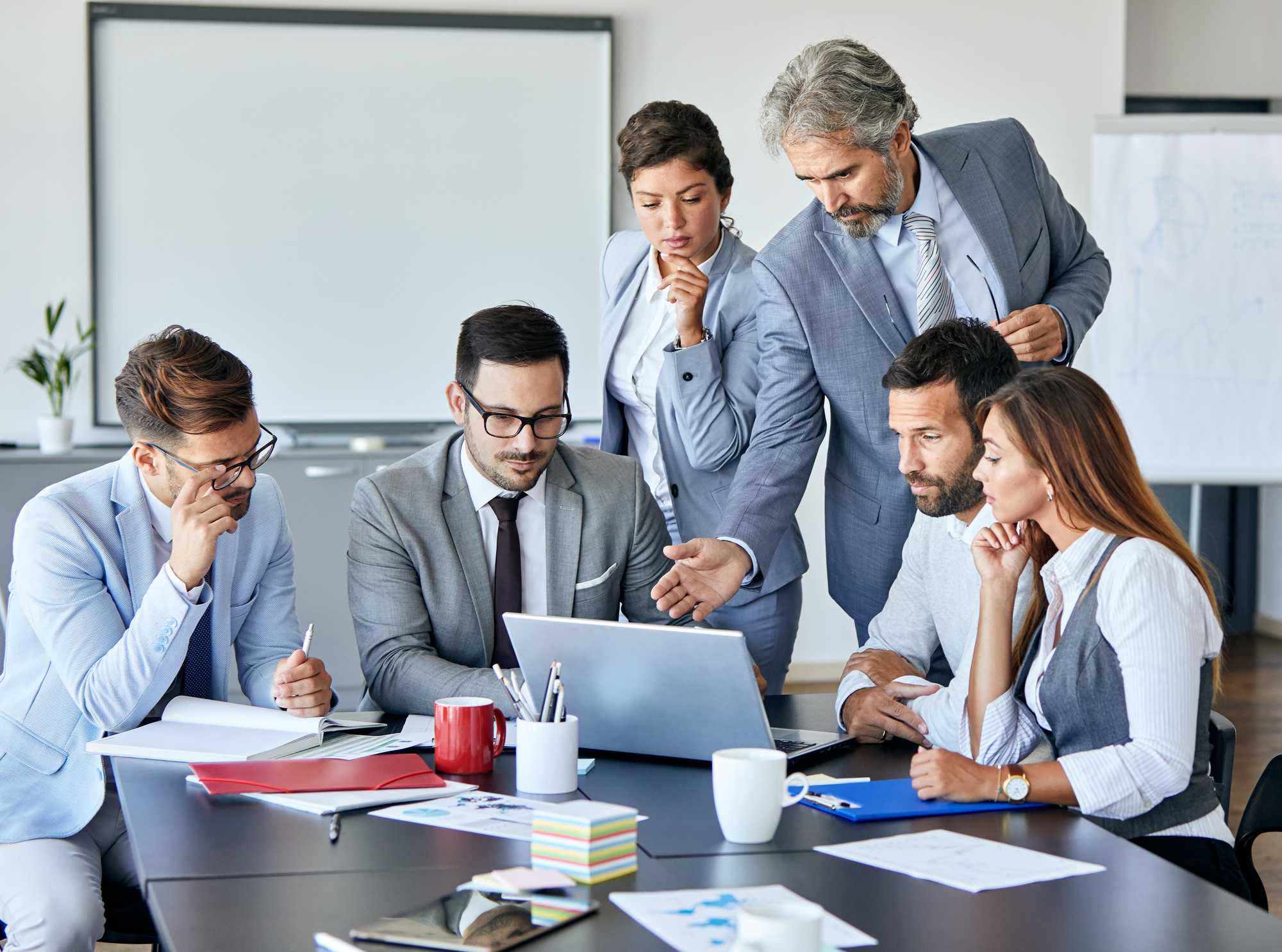 team meeting huddled around laptop, midfield, gray