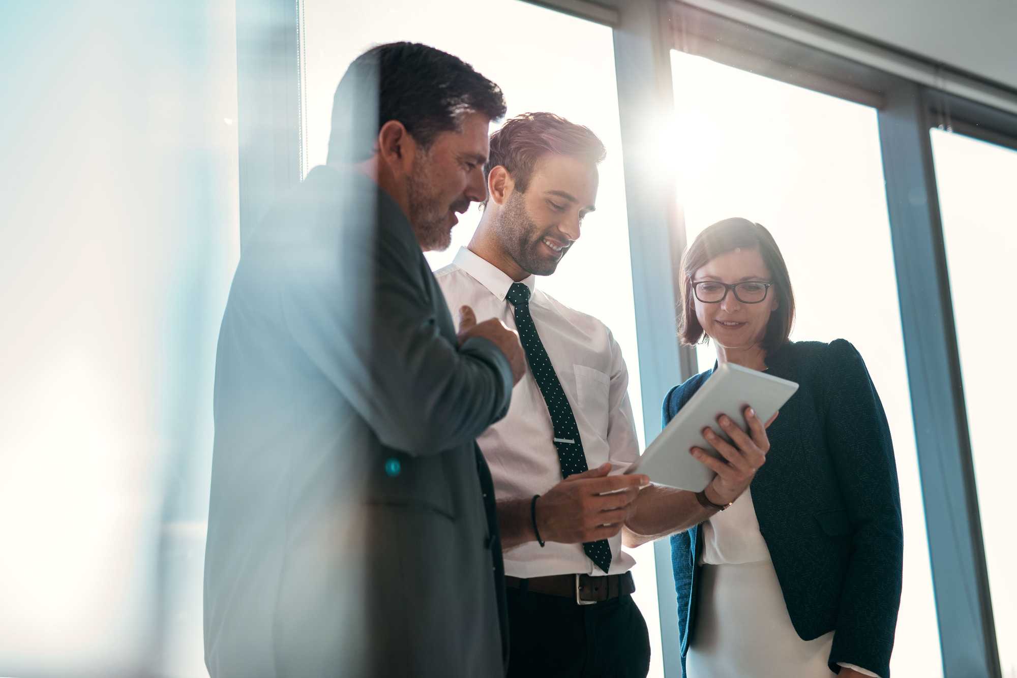 trois personnes debout, groupées autour d'un papier, gris, noir